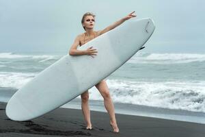 kvinna innehav surfingbräda och slående avslappnad utgör den där bara skriker sommar semester foto