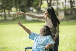 barnbarn pratar med sin mormor som sitter på rullstol, glatt koncept, lycklig familj foto