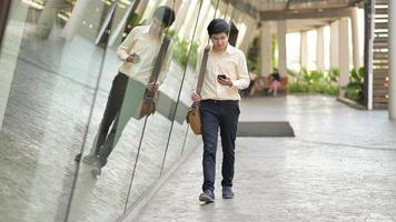 ny ung generation av företag med en axelväska titta på smarttelefonen i handen för att kontrollera arbetet. foto