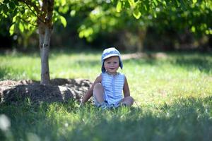 vacker baby pojke i barn trädgård poserar fotograf foto