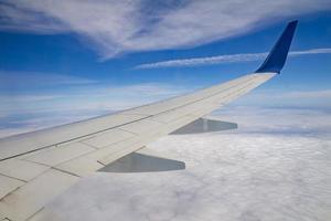 flygplansvinge på himlen och över havet med moln foto