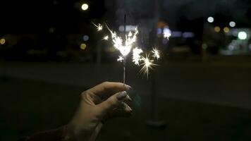 stänga upp av kvinna innehav sparkler på de gata. närbild av flicka med tomtebloss. kvinna hand innehav sparklers i de gata. Semester begrepp foto