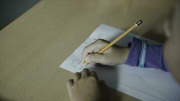 en söt liten pojke skrivning med en penna stänga upp. klämma. liten pojke är skrivning med en penna på papper foto