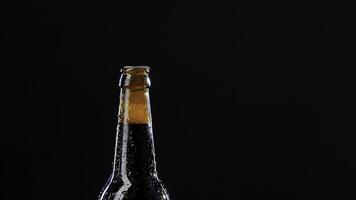 stänga upp av en hand öppning en glas flaska. video. alkoholhaltig dryck isolerat på svart bakgrund, begrepp av fest. foto