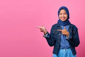 porträtt av leende ung asiatisk kvinna som pekar på att kopiera utrymme med fingret foto