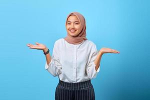 porträtt av glad ung asiatisk kvinna hålla handen närvarande annonser promo över blå bakgrund
