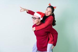 unga asiatiska par poserar på grön bakgrund med julkoncept foto