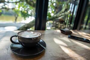 varm kaffe råna på trä tabell och natur se i lantlig by och solljus i kaffe affär foto