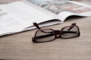 företag koncept, glasögon och Nyheter papper på på de trä tabell foto