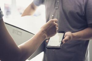 mjuk fokus hand kvinnor bifogar signatur i digital mobil telefon efter tar emot paket från kurir på Hem foto