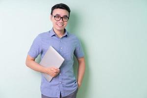 ung asiatisk affärsman poserar på grön bakgrund foto