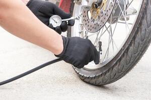 en man kolla upp uppblåsare tryck av de däck med motorcykel med elektrisk pump på väg grundläggande underhåll foto