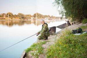 senior begrepp. pensionär fiskar på de flod i hans reserv tid. en användbar hobby, utomhus- aktiviteter i gammal ålder. kopia Plats. rostig båt foto