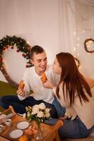 en ung Lycklig par i kärlek äter i en Foto studio. de kille och de flicka är rolig matning varje Övrig. Framställ för modeller i en studio för jul familj middag för ny år afton, frukost i säng