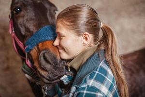 ung Tonårs flicka ryttare kissing henne kastanj häst. foto