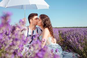 en par i kärlek under en vit paraply på en lavendel- fält kärlek foto