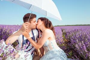 en par i kärlek under en vit paraply på en lavendel- fält kärlek foto