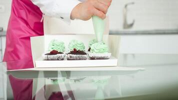 konditor dekorerar cupcakes, hemlagad matlagning, sötsaker. vispad grädde från spruta foto