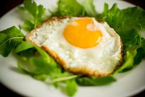 ett friterad ägg med arugula och sallad i en tallrik foto