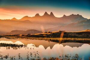 soluppgång lyser över lac guichard med arves massivet och sjö reflexion i höst på aiguilles d Arves, franska alperna, Frankrike foto