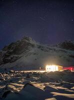 hus belysning på snöig med starry över berg foto