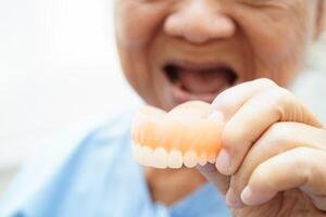 asiatisk senior kvinna patient bär tänder tandprotes in i henne mun för Tugga mat. foto