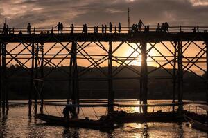 silhuett turister resa gående på trä- mån bro foto