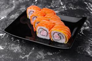 sushi rullar med lax och krabba på svart tallrik foto