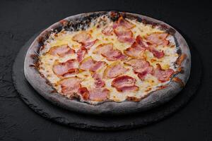 svart deg pizza med ost och skinka foto