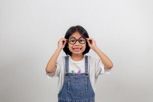 söt liten förskolebarnflicka isolerad på grå studiobakgrund bär glasögon titta på kameran, litet barn prova glasögon hos optiker, barn synkorrigeringsbehandlingskoncept foto