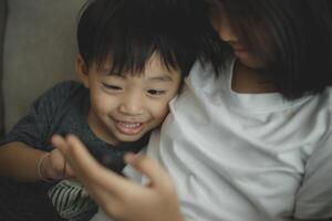 liten flickor och pojke syskon se på de telefon och leende. de håll en smartphone Kolla på videoklipp, lära sig, spela spel, och tala uppkopplad. internet för barn. föräldrar kontrollera foto