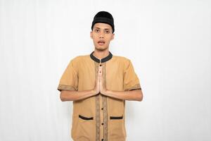 asiatisk muslim man bär brun muslim kläder ger en hälsning gest till gäster eller vänner. isolerat vit bakgrund. foto
