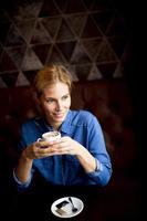 leende ung kvinna som dricker kaffe på café foto