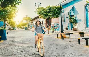 leende turist kvinna ridning en cykel på de gator av granada. skön flicka ridning en cykel på de gata av la calzada, granada, nicaragua foto