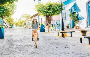 ung turist kvinna ridning en cykel på de gator av granada, nicaragua. Lycklig turist flicka ridning en cykel på calzada gata foto