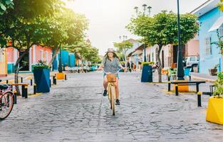 Lycklig turist flicka ridning en cykel på calzada gata. ung turist kvinna ridning en cykel på de gator av granada, nicaragua foto
