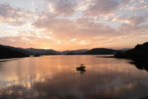 kvällssjön speglade solnedgången och bergen foto