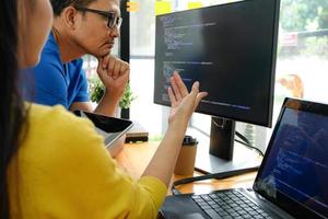 asiatiska kvinnliga programmerare som bär gula skjortor pekar på sin bärbara skärm för presentation för chefer. foto