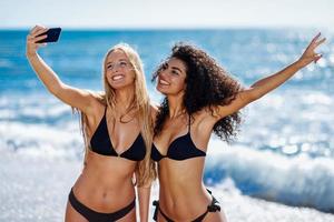 två kvinnor som tar selfiefotografi med smartphone på stranden
