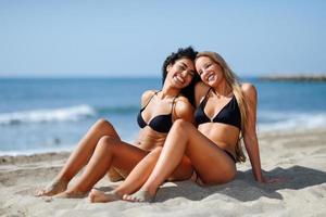 två unga kvinnor med vackra kroppar i badkläder på en tropisk strand