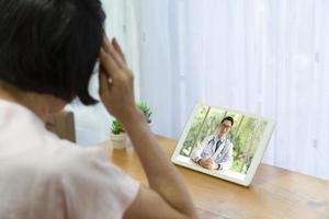 äldre patient har huvudvärk så hon konsulterar läkare via videosamtal online. telemedicin och vårdkoncept foto