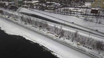 topp se av vinter- vägbank av flod nära stad. klämma. flod från vägbank nära stad i vinter. man promenader längs flod vägbank på bakgrund av stad foto