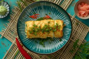 ai genererad folk stil tamagoyaki japansk omelett på mönstrad tallrik foto