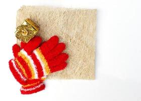 julstickade röda handskar och guldpresentask på vit bakgrund med plats för text