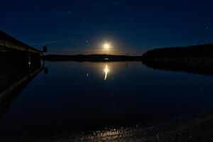 solnedgång på en sjö i Sverige. de månsken är reflekterad i de lugna vatten. foto