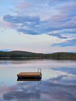 simning ö i Sverige på en sjö på solnedgång. moln reflekterad i de vatten. foto