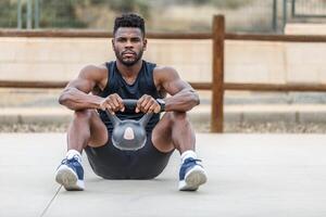 muskulös afrikansk amerikan man utövar med kettle i sporter jord foto