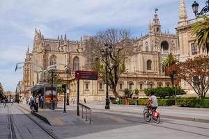 Sevilla, Spanien, 2017 - människor som cyklar nära en spårvagnshållplats framför katedralen i Sevilla. foto