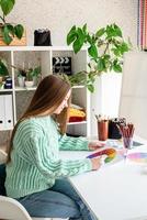ung tonårskvinna konstnär som håller färgpalett som arbetar i hennes studio foto