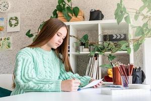 ung tonårskvinna konstnär som håller färgpalett som arbetar i hennes studio foto